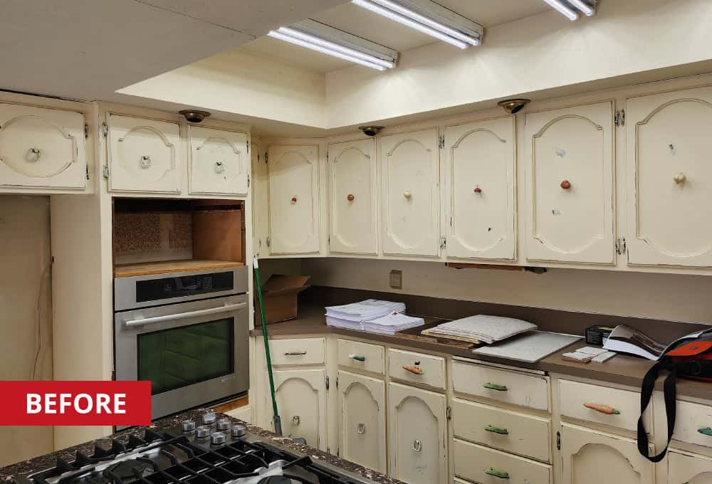 Off-white built-in kitchen cabinets with brown countertop.