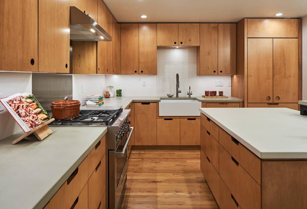 Kitchen with plywood cabinets and drawers with maple veneer, a kitchen island, and concrete countertops.