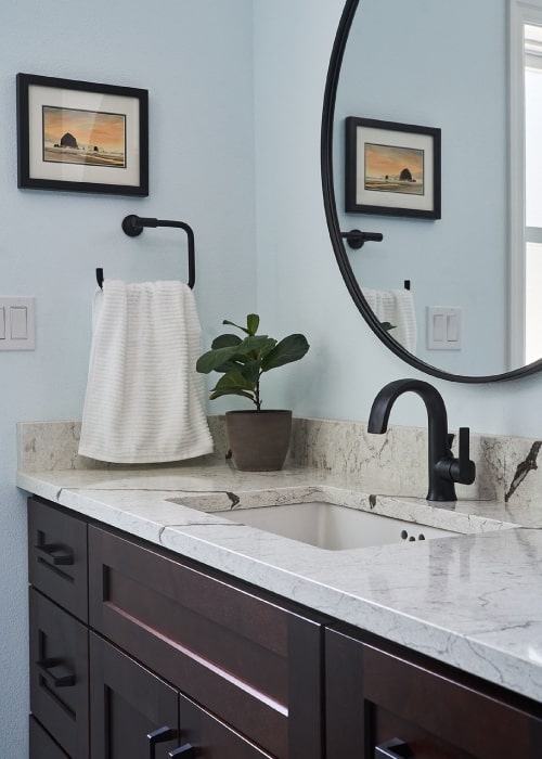 Bathroom counter from Architectural Surfaces with Moen Doux matte black bathroom sink faucet and hand towel holder.