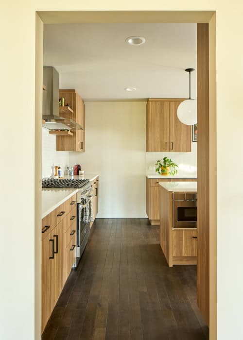 Mid-century modern kitchen with wood cabinets, large kitchen island, bright yellow chairs, and pendant lights.