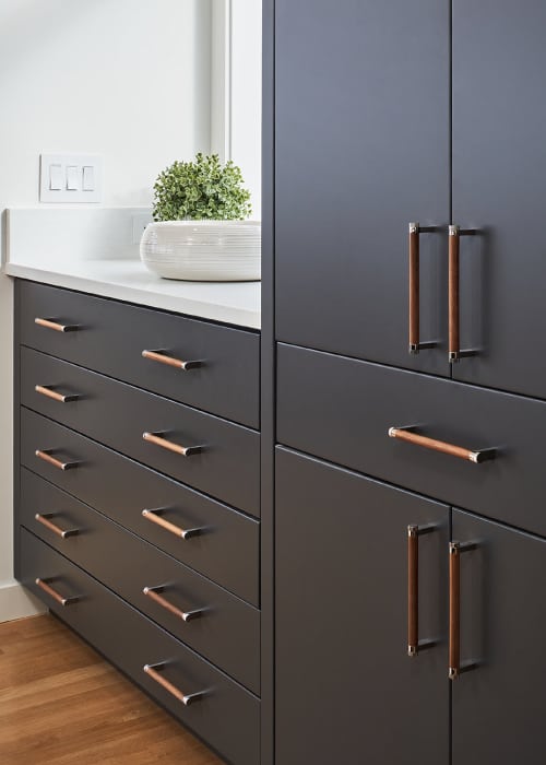Dark kitchen cabinets with brass pull handles.