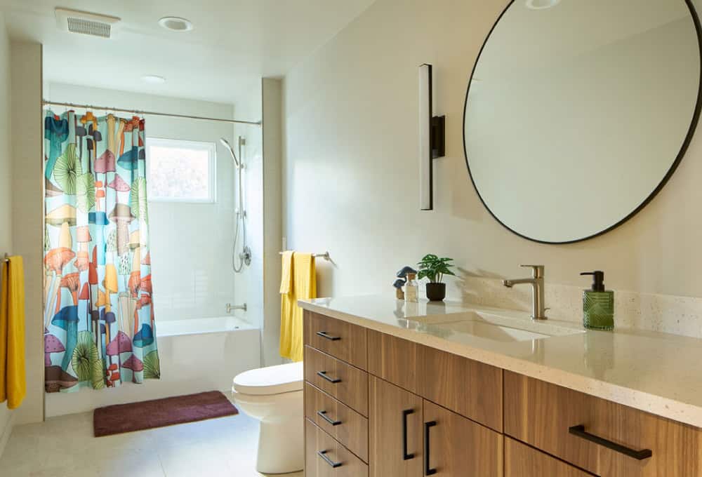 Bathroom with modern mid-century style cabinets and large round mirror.