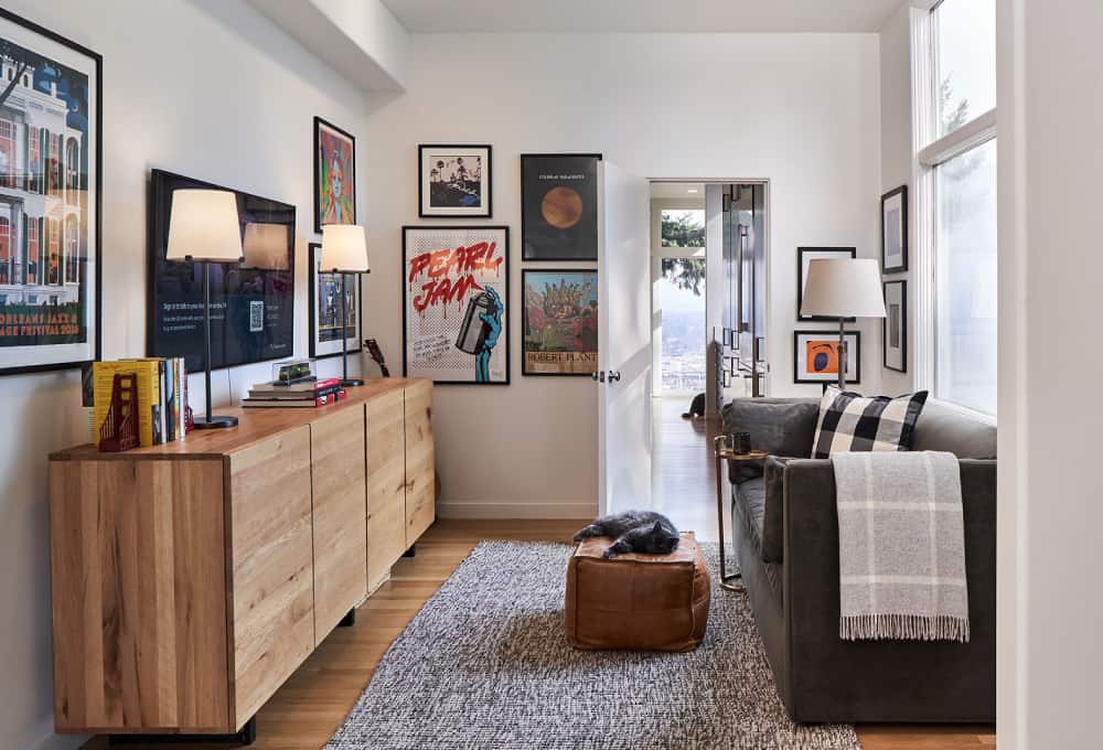 Remodeled den with a wooden dresser, wall art, and a couch.