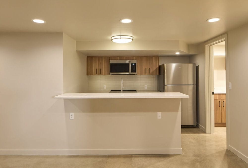 Basement kitchen with bar, sink, refrigerator, and microwave.