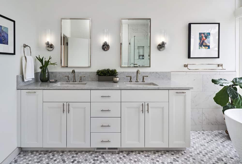 Double vanity with white cabinets and mirrors on the wall.