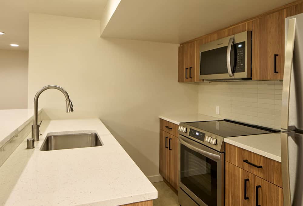 White kitchen island with sink, built-in cabinets, and stove and microwave.