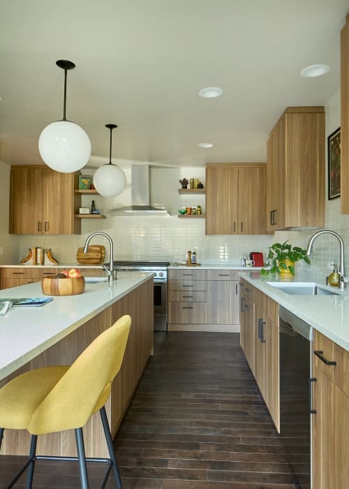 Mid-century style kitchen with pendant lighting, yellow chairs, and built-in cabinets.