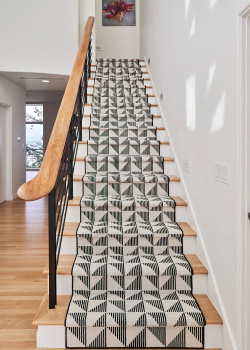 Wooden staircase with geometric-patterned Stark Carpet on the stairs.
