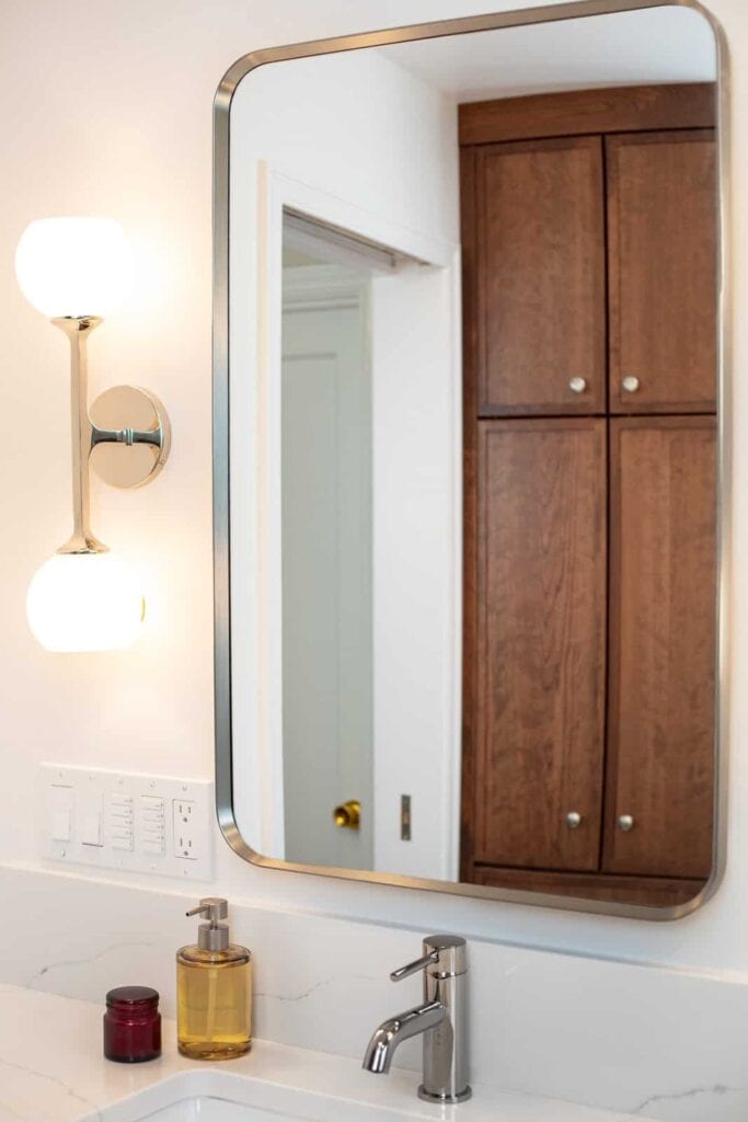 A bathroom mirror with wood cabinets in the reflection