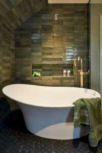 A large freestanding bathtub in a wet room and a squirt gun in the niche 