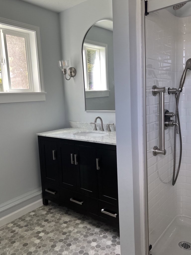 A remodeled bathroom vanity and shower with nickel hardware and fixtures specified for aging in place