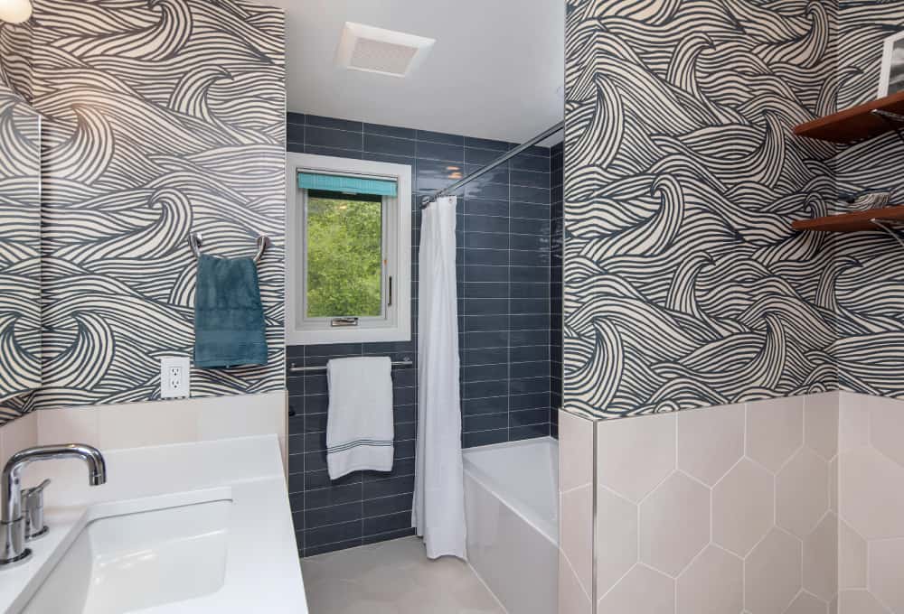 Bathroom shower tucked away behind a wall with a white shower curtain.