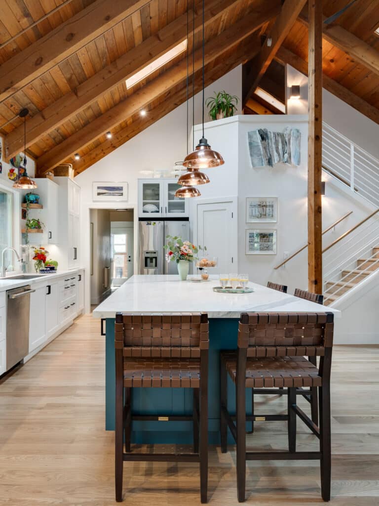 Kitchen remodel with vaulted wood ceiling, marble island, and teal cabinetry in an open great room.