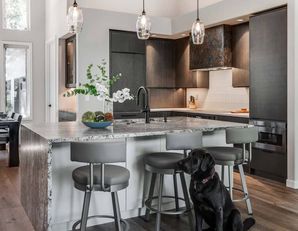 Modern kitchen remodel with dark wood cabinetry, granite island, and vaulted ceiling with pendant lighting.