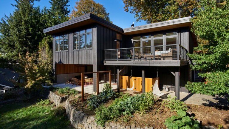 The rear of the house from the garden, with the deck above and a covered outdoor room at grade.