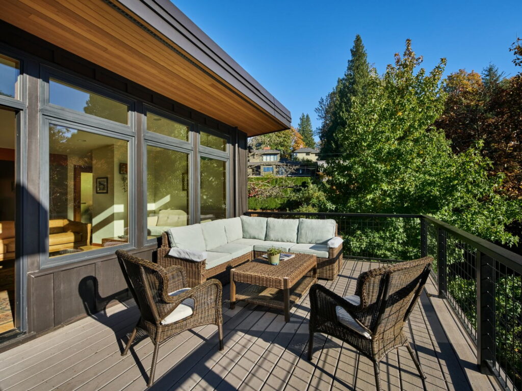 Upper deck furnished with a sectional, looking along the cedar soffit toward the treetops.