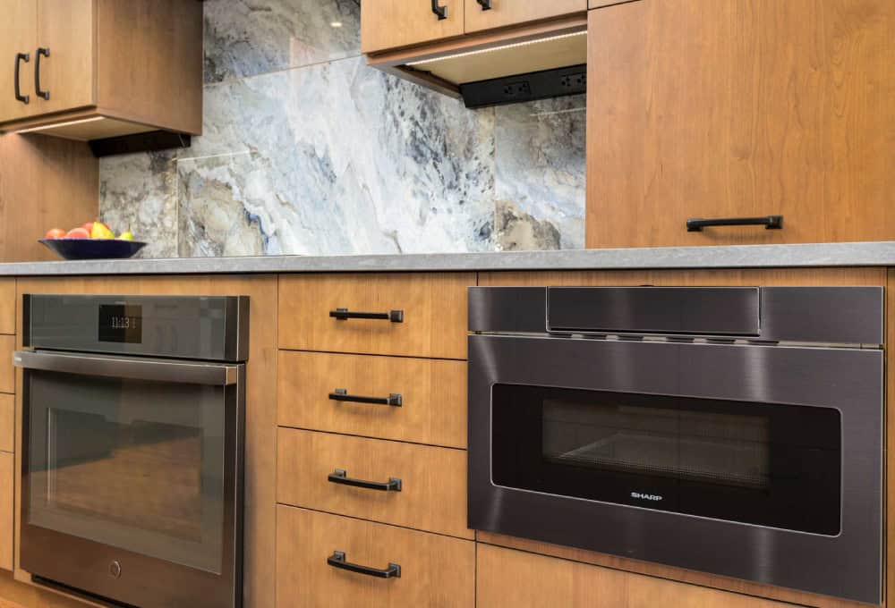 Walnut slab door drawers from Decor Cabinets with a built in oven and microwave.