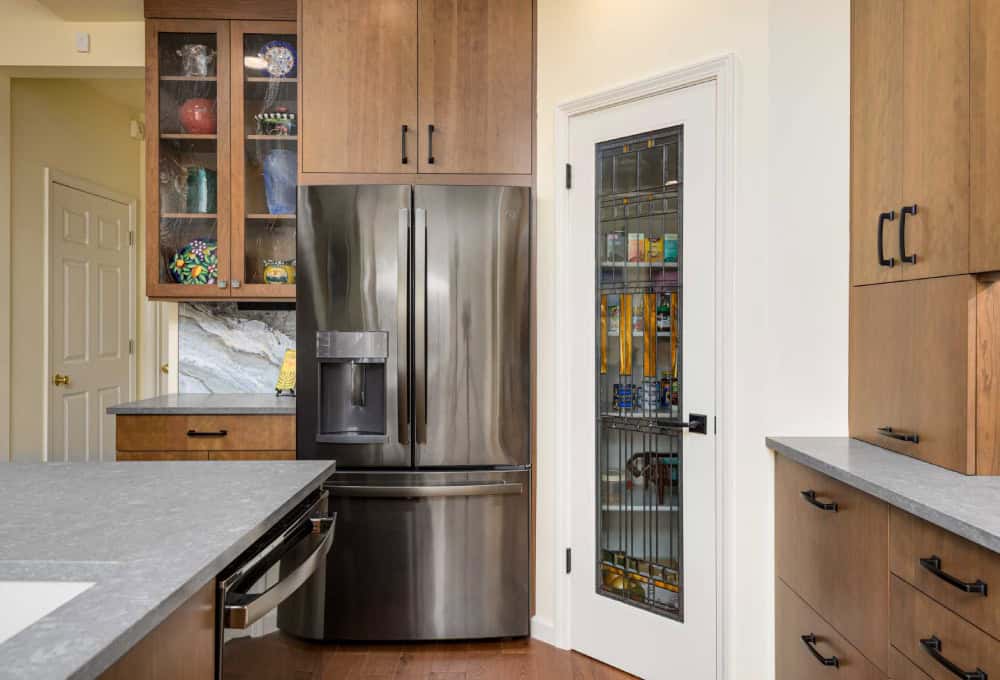 Stainless steel double-door refrigerator to the left of a pantry door.