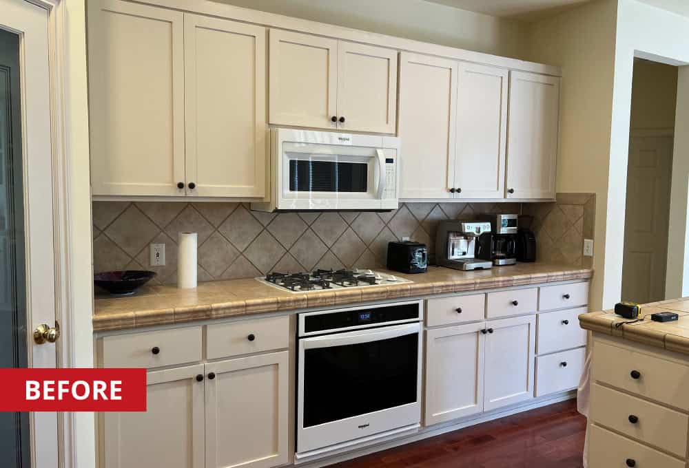 White kitchen cabinets along the wall with a wall-mounted microwave.