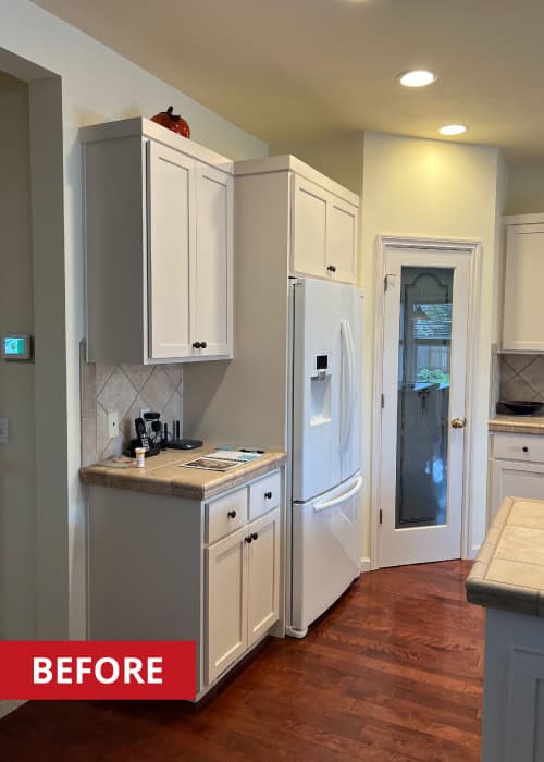 Two door cabinets to the left of a white refrigerator.