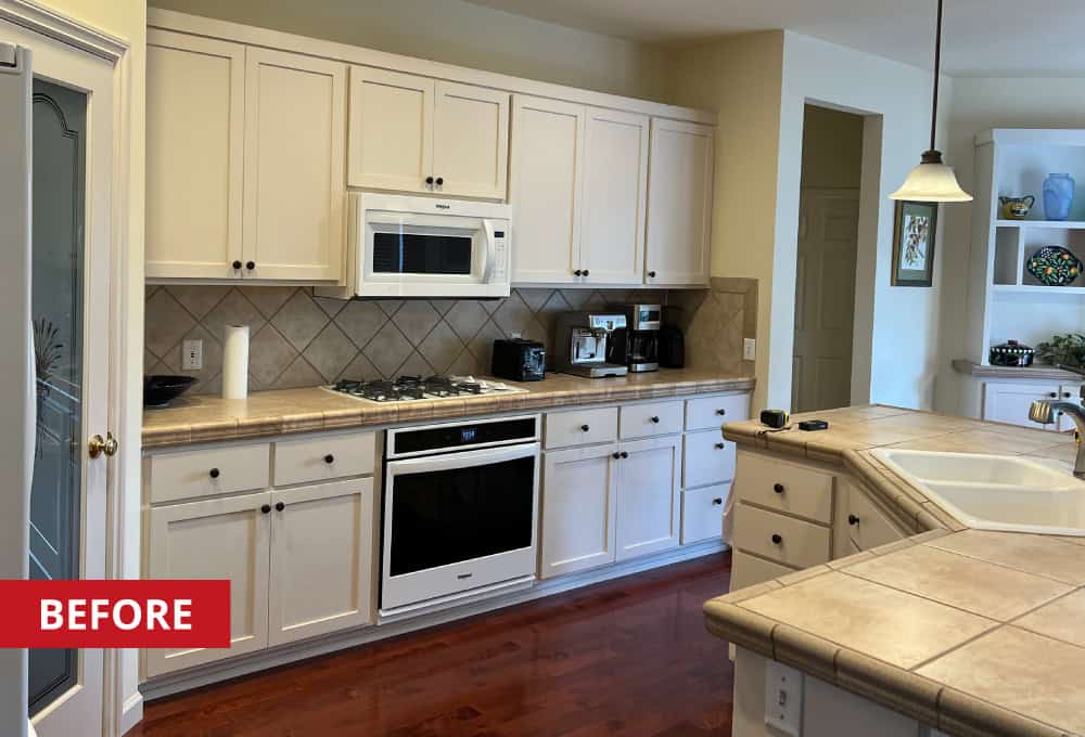 White kitchen cabinets along the wall with a wall-mounted microwave.