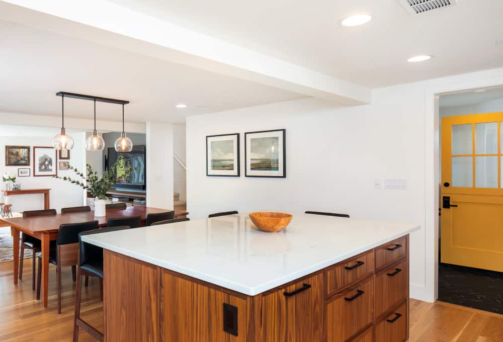 Kitchen with a large center island with four wooden stools around the countertop.