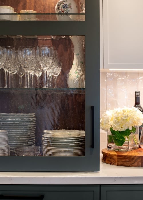 Plates and glass drinkware storage built on top of a kitchen counter.