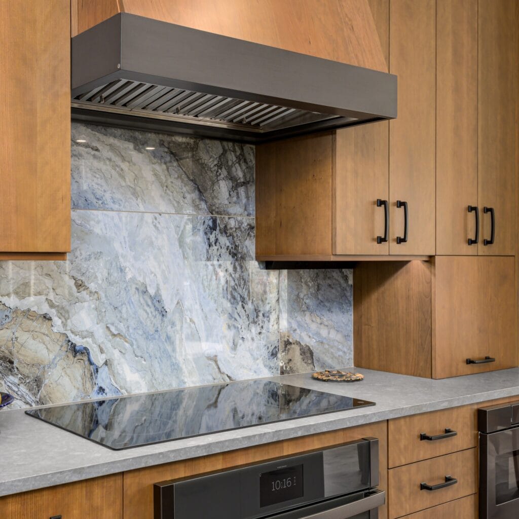 A remodeled kitchen with stained wood cabinets, an induction cooktop, and an ocean-inspired porcelain backsplash