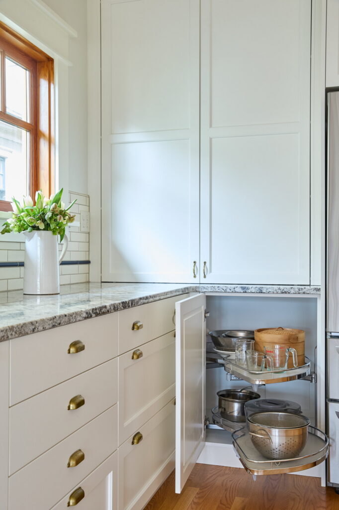 Corner cabinet with its swing-out shelving pulled forward, holding mixing bowls, measuring cups, and a steamer.