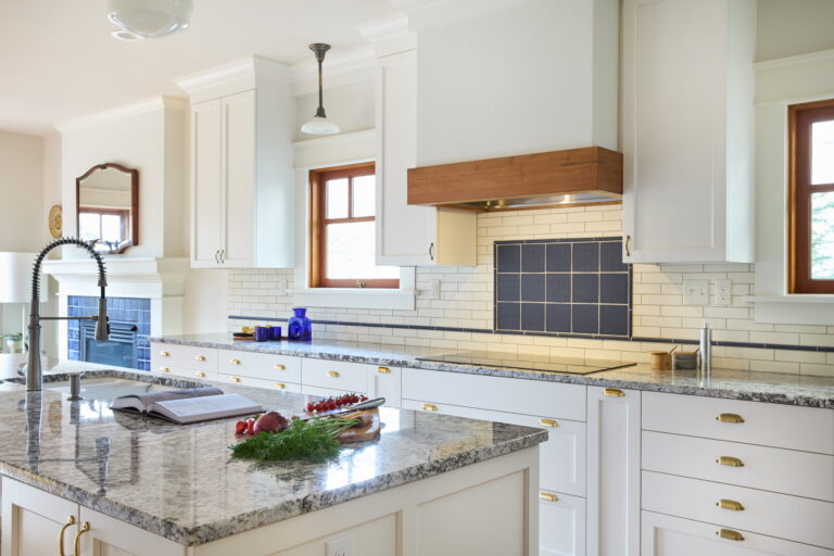 The kitchen island and cooktop wall, with the adjoining room’s tiled fireplace visible at left.