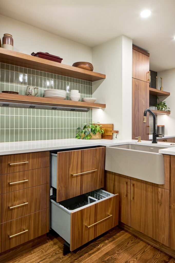 Concrete apron-front sink beside panel-front dish drawers, under the green stacked tile.