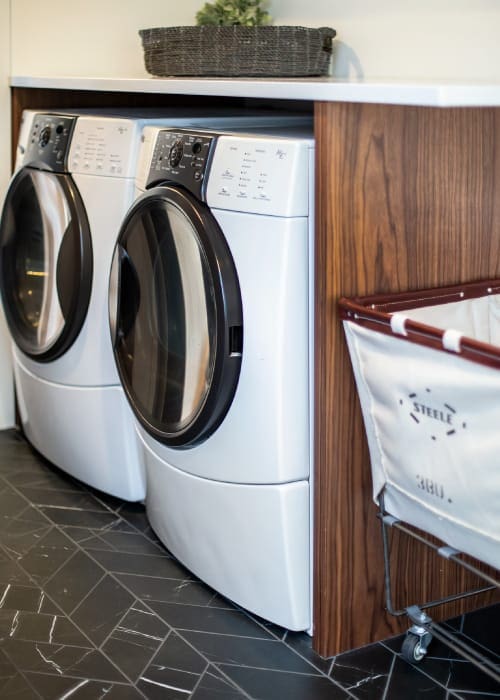 Laundry washer and dryer stowed beneath a white countertop in a laundry room.