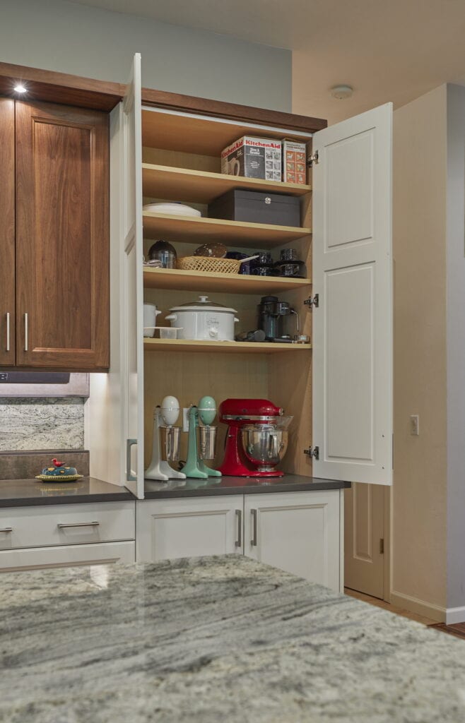 Appliance pantry with its doors open, holding stand mixers, small appliances, and adjustable shelving.