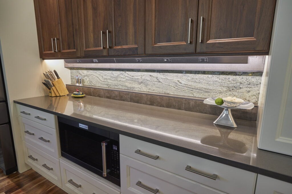 Granite-slab backsplash and quartz counter above a built-in microwave drawer and painted cabinetry.