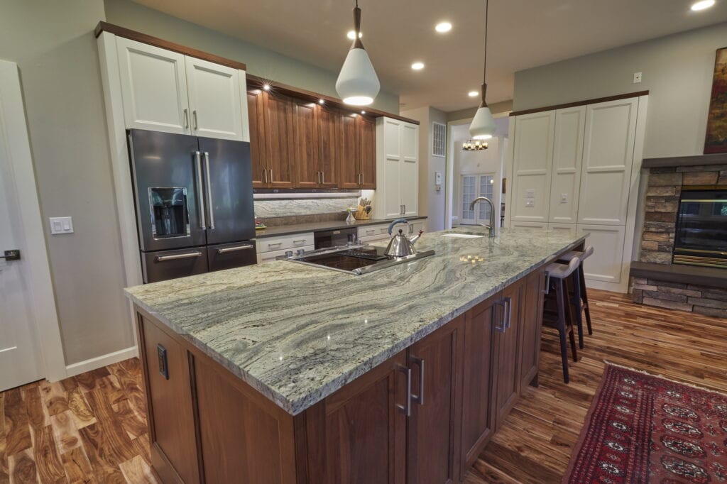 The island and refrigerator wall, with walnut upper cabinets over a granite-slab backsplash.