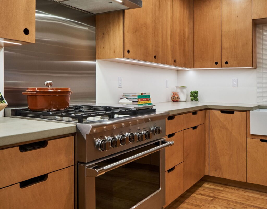 Professional gas range with a griddle, set against a full stainless backsplash under the hood.