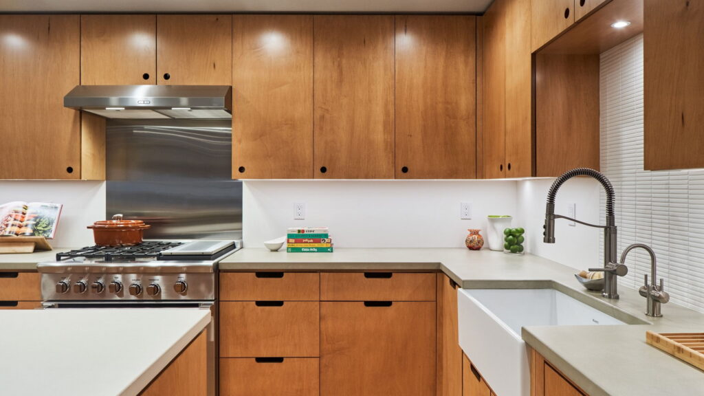 Working run of the kitchen with a professional gas range under a stainless backsplash, beside the apron-front sink.