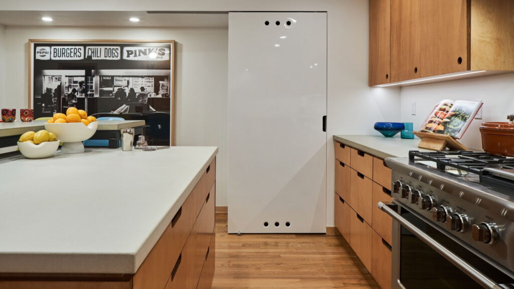 The island looking toward the range, with a white sliding panel concealing storage on the far wall.
