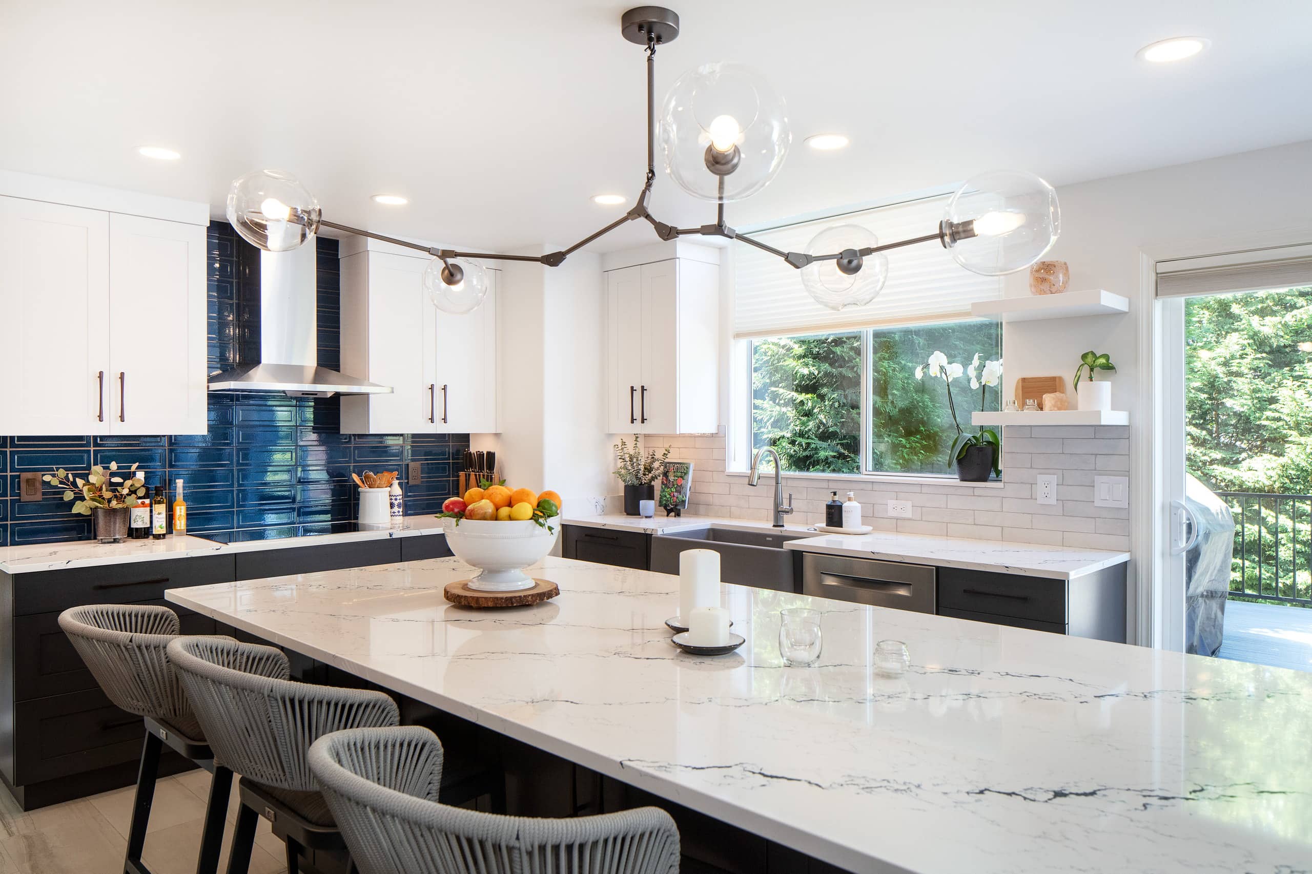 Remodeled Renton kitchen with a quartz-topped island, charcoal shaker cabinetry, and a glossy navy tile backsplash behind the cooktop.