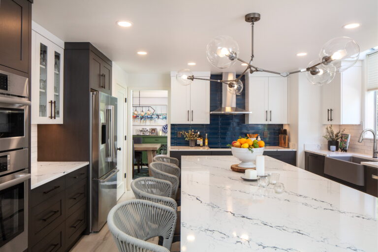 Wide view across the island toward the dining room doorway, with the navy tile range wall at center.