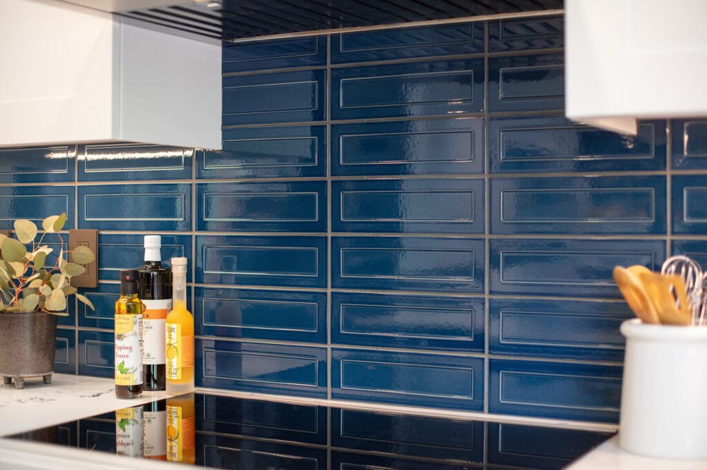 Detail of the glossy navy picket tile backsplash with its beveled recessed face.