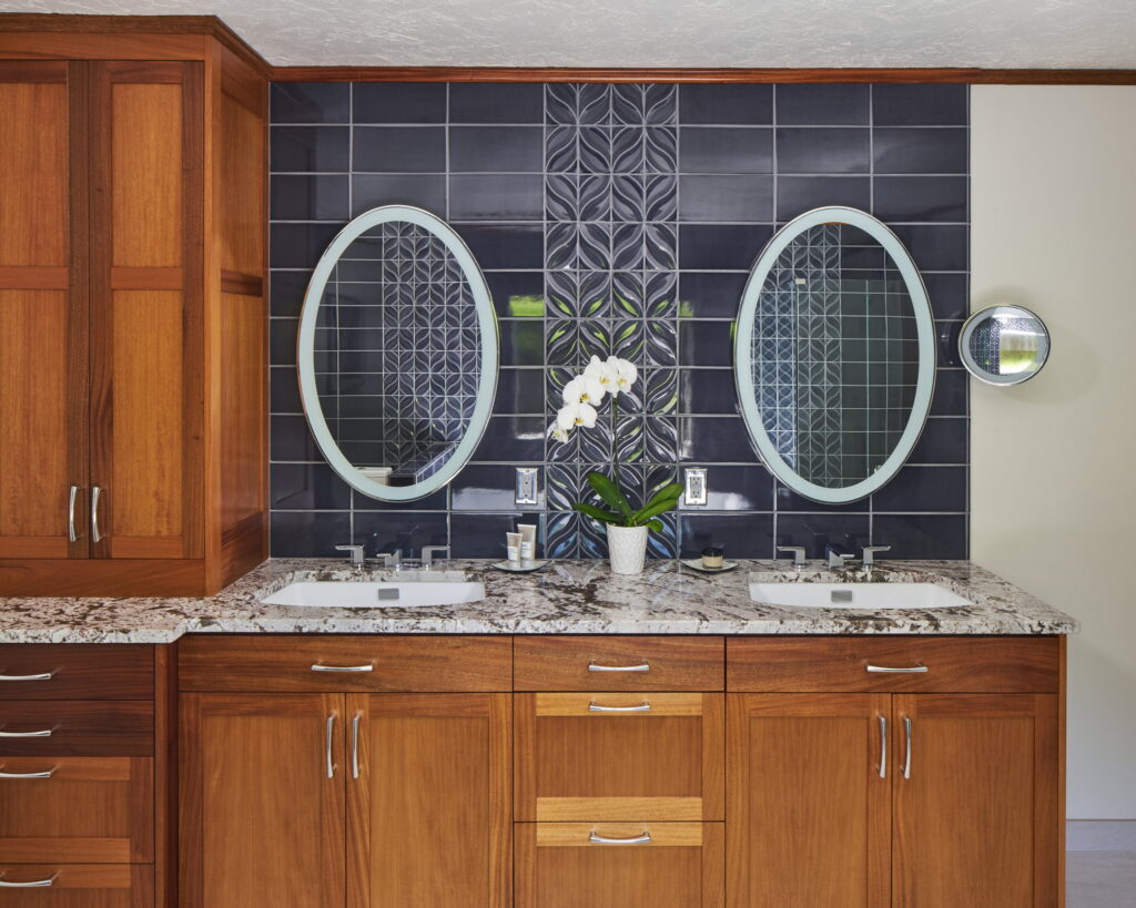 Double vanity with a tall linen cabinet, granite counters, and undermount sinks.