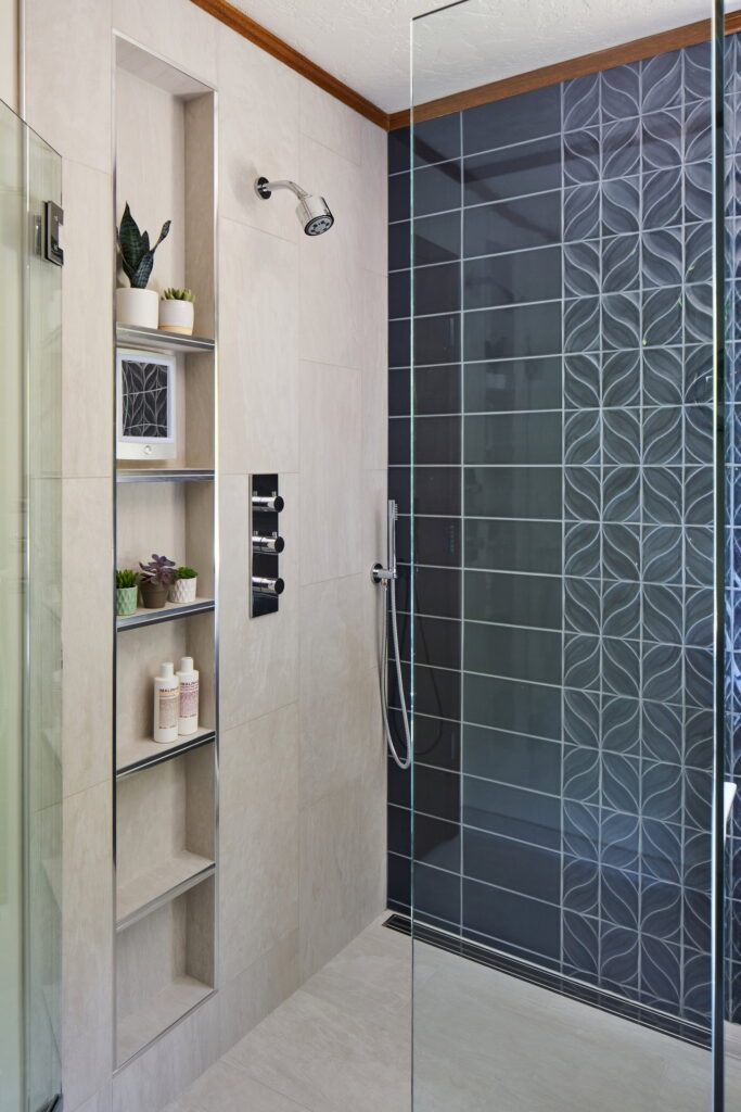 Recessed shower niche with chrome-edged shelves, beside the thermostatic valve controls.