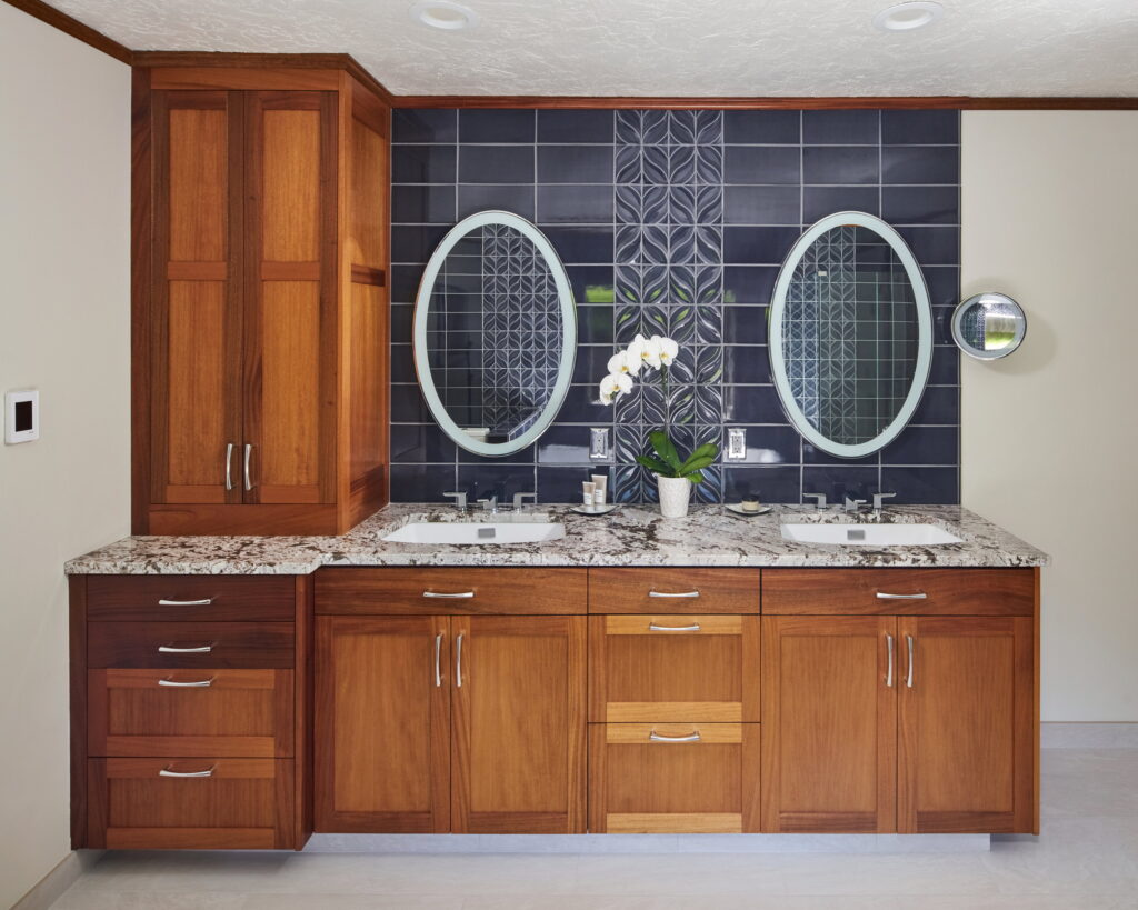 Vanity run and linen tower, with the navy tile carried up behind the mirrors.