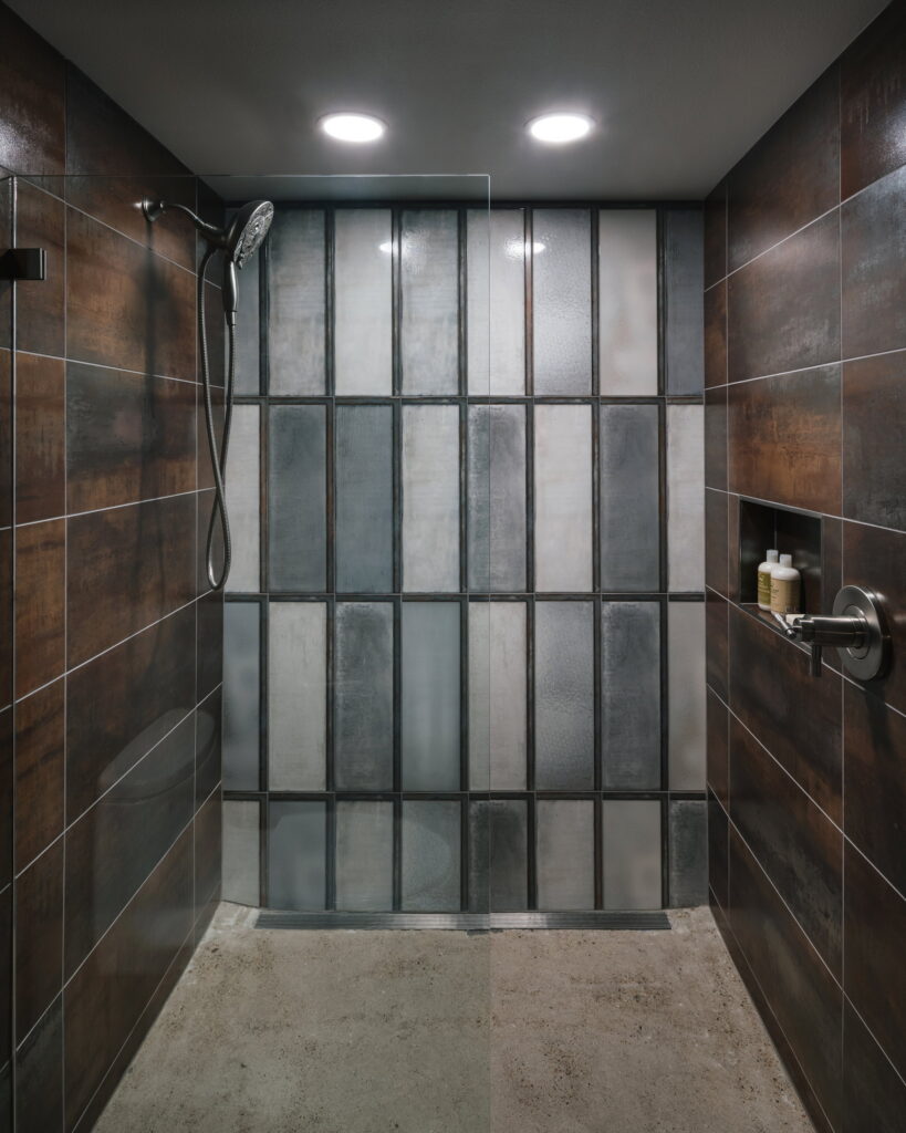 Curbless shower with a linear drain, metallic wall tile, and a polished concrete floor.