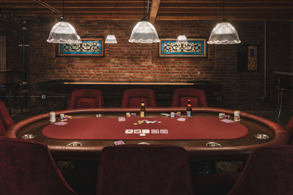 Poker table viewed head-on, with the wall-mounted television and card art behind.