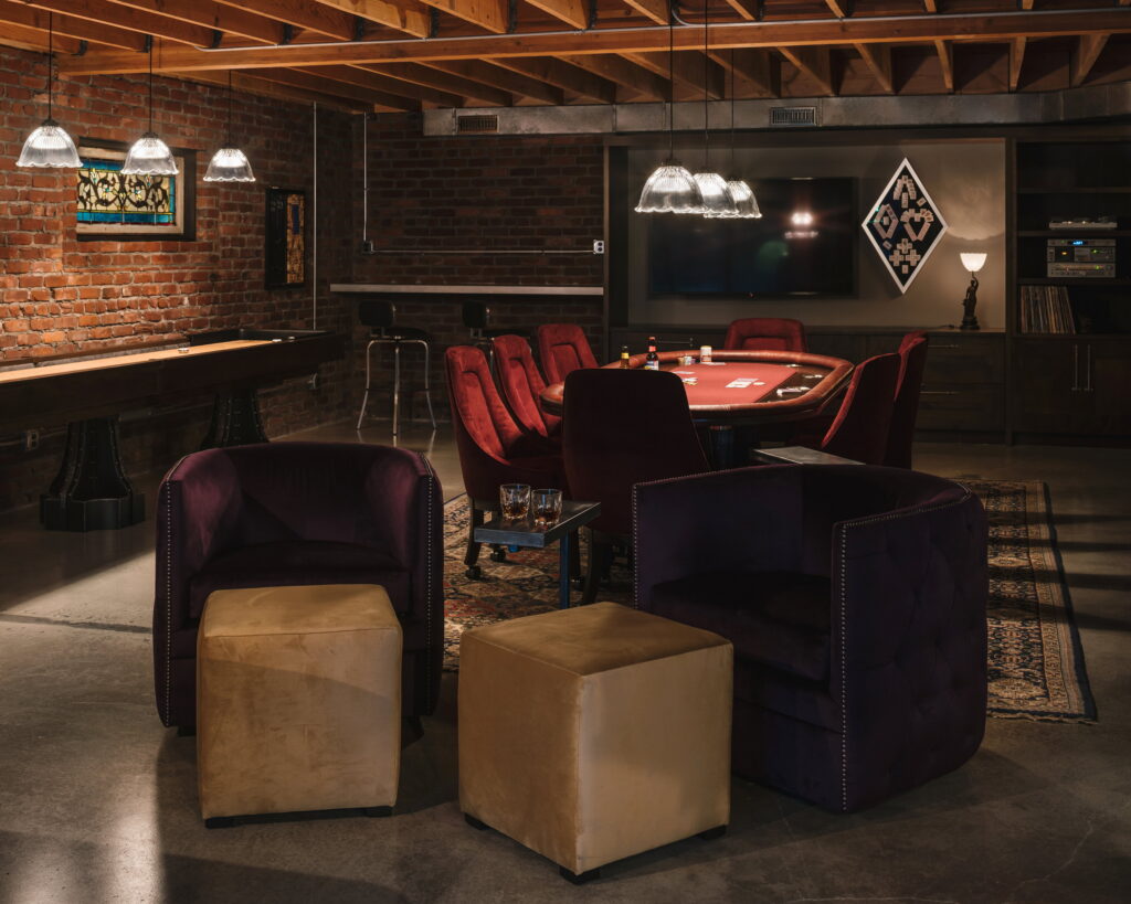 Purple velvet chairs and ottomans arranged on a patterned rug between the shuffleboard and poker areas.