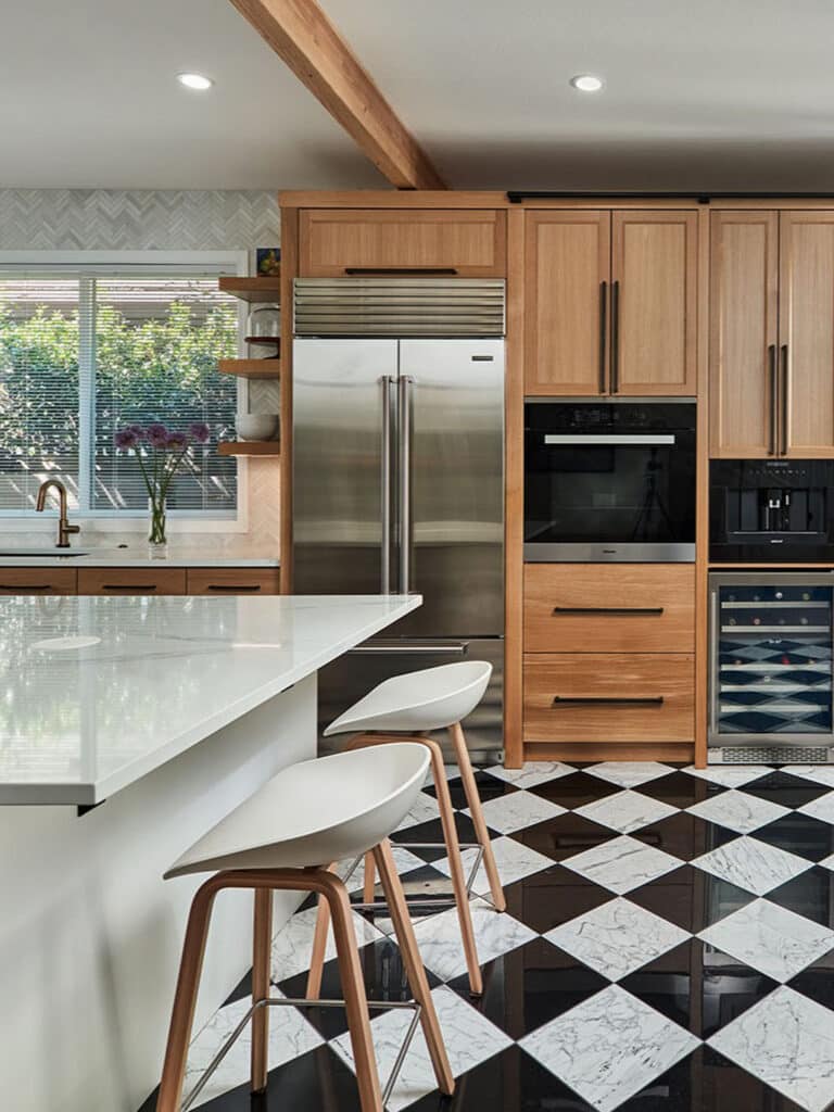 Kitchen remodel with wood cabinetry, black-and-white marble checkerboard floor, and stainless appliances.