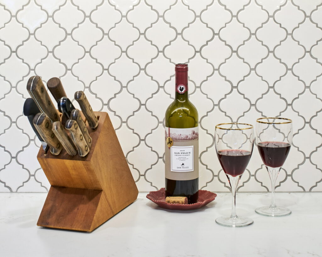 The lantern tile backsplash behind a wood knife block and quartz counter.