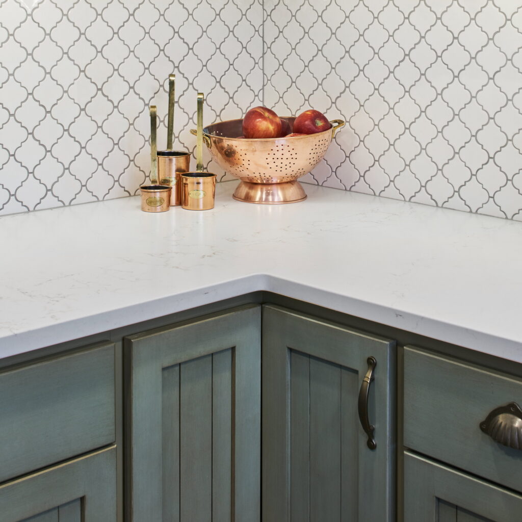 Close view of the lantern tile, quartz counter edge, and glazed green cabinet finish.